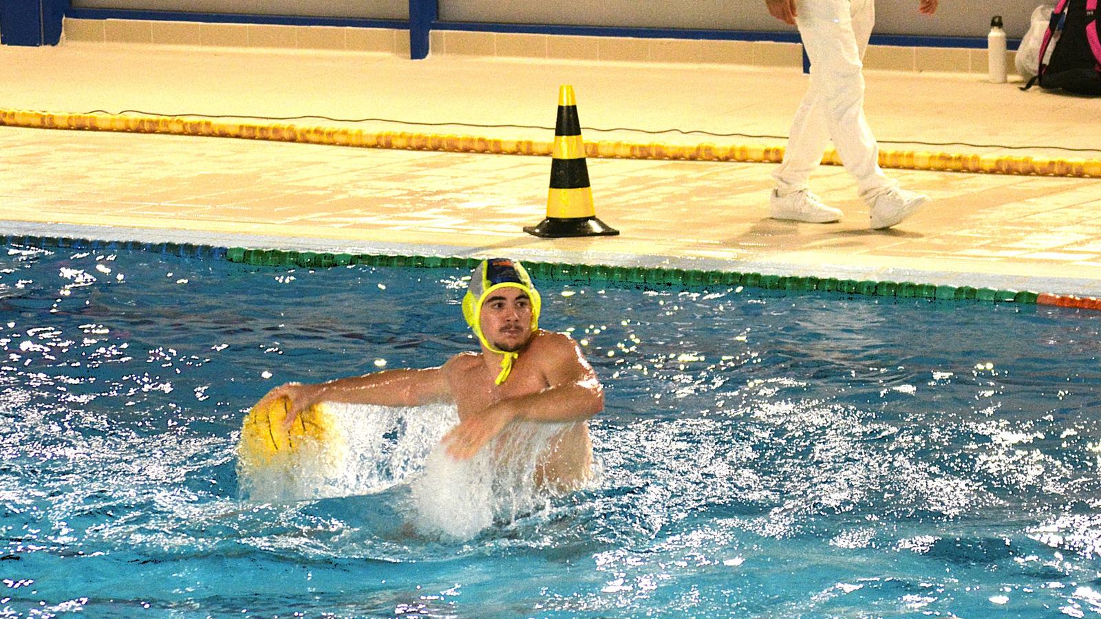 Jugador de waterpolo del Getxo avanza con el balón amarillo en una piscina durante un partido.